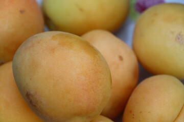 Ripe washed yellow apricots lying in plate on table macro shot