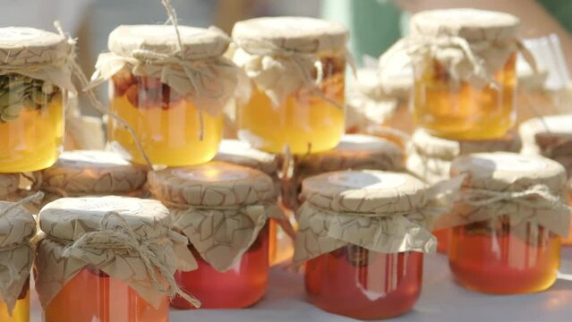 Rows of jars of bright yellow orange honey at the outdoor market