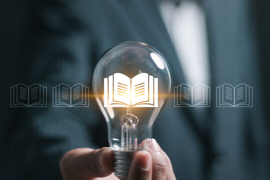 E-library concept. Businessman hold light bulb with virtual Ebook icons for electronic books online, knowledge base on internet, digital library or e-library.