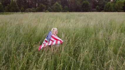 American woman proudly holding American flag at sunset field, celebrate 4th of July