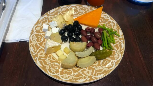 Assortment of different cheeses and pickled vegetables. An antipasto appetizer plate.