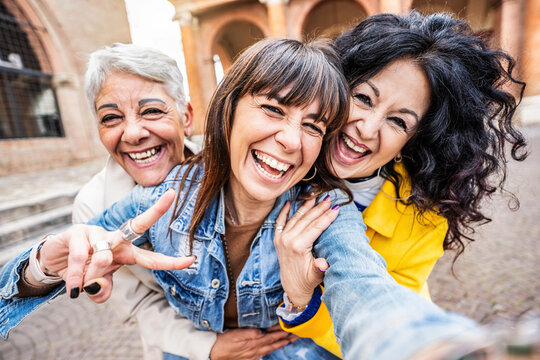 Three senior women taking selfie photo with smart mobile phone device outside - Happy aged people having fun together walking on city street - Life style concept with mature females hanging out