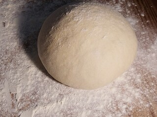 Dough of wheat on a table sprinkled with flour