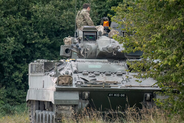 soldier atop British army Warrior FV510 Infantry Fighting Vehicle in action on a military exercise