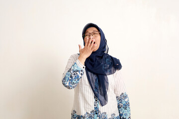 Portrait of sleepy asian elderly muslim woman standing while yawning