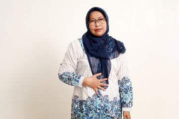 Asian elderly muslim woman feeling uncomfortable with her stomach