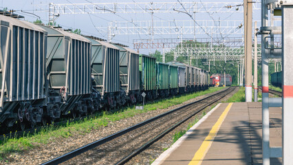 The railway platform at the station. A place for passengers to board the train. Railway tracks for railway transport. Freight cars at the station. Transportation of goods by rail.