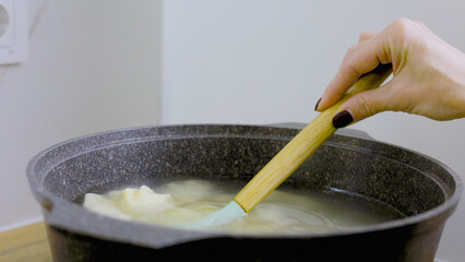 A young woman cooks dumplings, ravioli in a saucepan