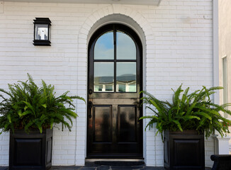 white brick building with glossy black arched front door