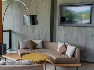 An executive lounge with a semi-circular sofa, a small roundtable, and a curved lamp.