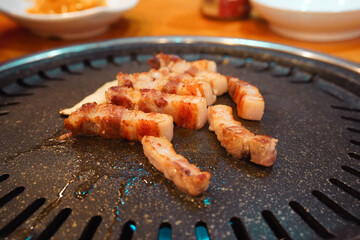 焼肉店でサムギョプサルを鉄板で焼く、食べる