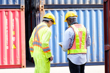 Engineer wearing safety helmet working in container warehouse.