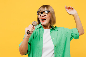 Elderly singer happy blonde woman 50s years old wear green shirt glasses casual clothes sing song...