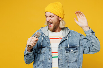 Young happy fun singer Caucasian man wears denim shirt hoody beanie hat casual clothes sing song in...
