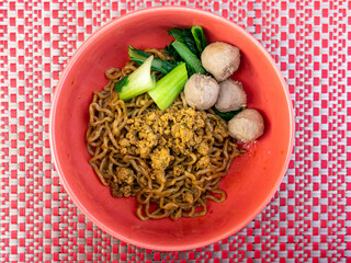 A Bowl of Dry Chicken Noodle with Four Meatballs and Slices of Mustard Greens