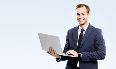 Happy smiling young business man wear black suit, necktie using laptop computer, isolated gray grey background, copy space area for ad text. Businessman holding notebook at studio concept image.