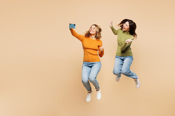 Full body young friends two women they wear orange green shirt casual clothes jump high do selfie...