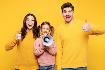 Young parents mom dad with child kid girl 7-8 years old wear pink sweater casual clothes hold megaphone scream about sale Hurry up show thumb up isolated on plain yellow background Family day concept