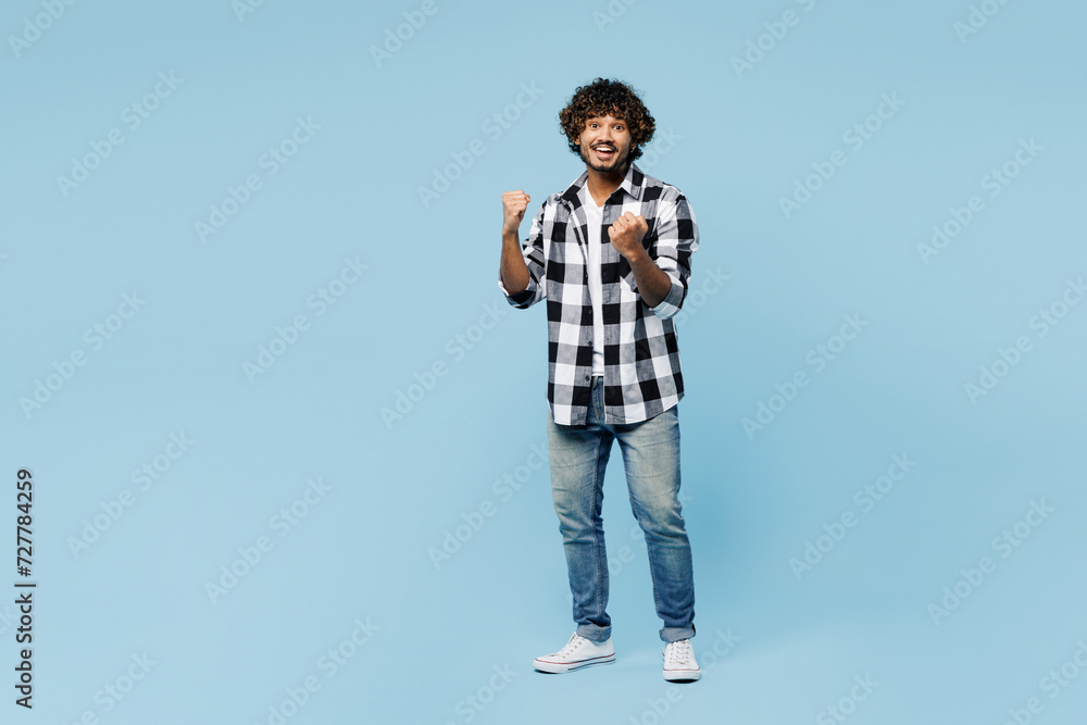 Wall mural Full body young Indian man wear shirt white t-shirt casual clothes doing winner gesture celebrate clenching fists say yes isolated on plain pastel light blue cyan background studio. Lifestyle concept - Wall murals