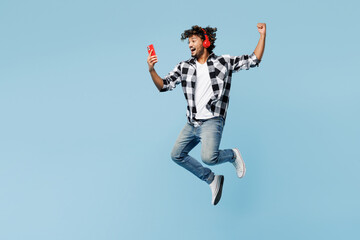 Full body young Indian man wear shirt white t-shirt casual clothes jump high use mobile cell phone...