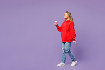 Full body side view young blonde woman she wear red hoody casual clothes hold takeaway delivery...