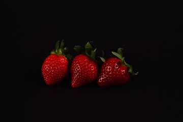 Red ripe strawberries lie on a black background