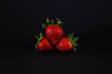 Red ripe strawberries lie on a black background