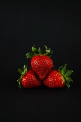 Red ripe strawberries lie on a black background
