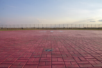 Helicopter pad. A red landing area for helicopters at sunset. Helipad landing lights. Illumination equipment for helicopter landing pads.. - obrazy, fototapety, plakaty