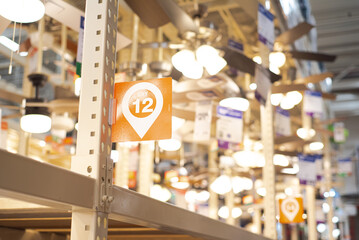 Lighting department with aisle and bay number wide variety of modern ceiling fans blurred bokeh...