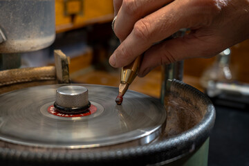 Stonecutter faceting red garnet stone on the metal dop stick into the round stone shape.