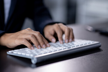 Close-up shot of a man's hands typing on a backlit mechanical keyboard in a dark room.
