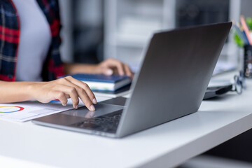 Hands of Young Asian woman working on computer at table in office, closeup. Banner design during work over new business project by table.