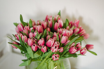 Close-up photo of bouquet with beautiful fresh flowers. Lot of tulips in vase with water. Women's day