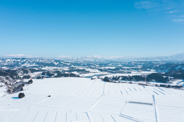 ドローン撮影：冬の青空の下雪に覆われた田舎町