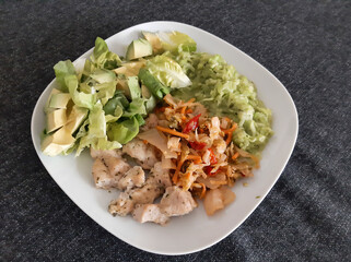 Homemade grilled chicken cooked zucchini, green salad, sliced avocado and Kimchi