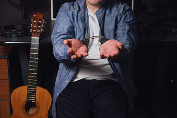 Sad musician handcuffed at a recording studio. Workplace of a sound engineer in a recording studio
