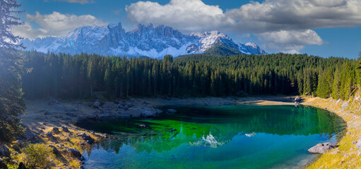 Lago di Carezza, an alpine marvel with emerald waters, cradled by spruce trees, framed by the...