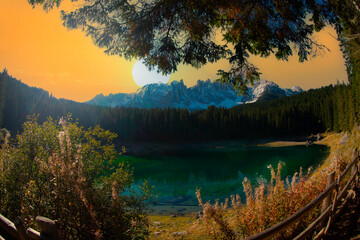 Lago di Carezza, an alpine marvel with emerald waters, cradled by spruce trees, framed by the...