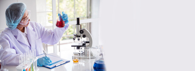 Banner Asian woman scientist hand write note research in medical lab look at science microscope. Panorama biology chemistry lab. Asian Female technician laboratory using microscope with copy space