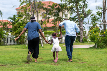 Obraz premium Portrait of enjoy happy love black family african american father and mother with little african girl child smiling and play having fun moments good time in park at home