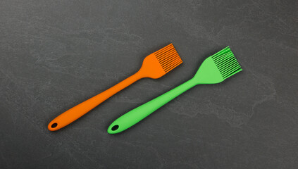 Two silicone culinary brushes on black slate board