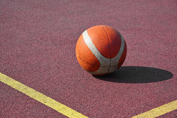 Orange basketball ball on red outdoors court