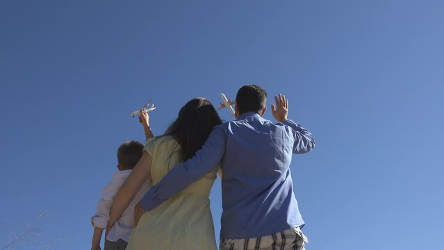 Young family waving hands to airplane flying over