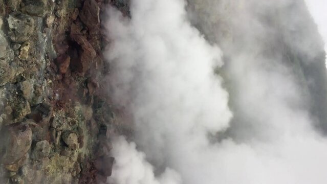 View on geyser field at the foot of the Mutnovsky volcano (popularly known as the Lesser Valley of Geysers) in cloudy summer day in Kamchatka, Russia. Real time handheld vertical video.