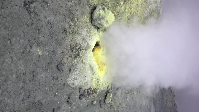Close-up view of hot fume going up from yellow fumarole in Mutnovsky volcano crater in Kamchatka, Russia. Real time handheld vertical video. Volcanic activity theme.