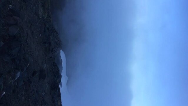 View from Avachinsky volcano slope of snowy Koryaksky volcano peak rising over clouds in a sunny morning in Kamchatka, Russia. Real time handheld video. Extreme travel theme.