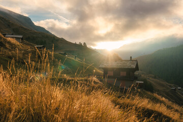 Sunrise shines over wooden cottage on hill among the Swiss Alps in mountain village at Switzerland