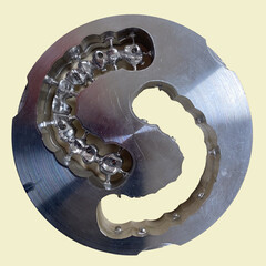 photo of the jaw, a laser cut impression in a titanium metal block, a model of teeth, dental technique