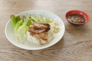 slice grilled pork neck topping rice with cucumber and garlic dipping spicy chili tamarind sauce on plate